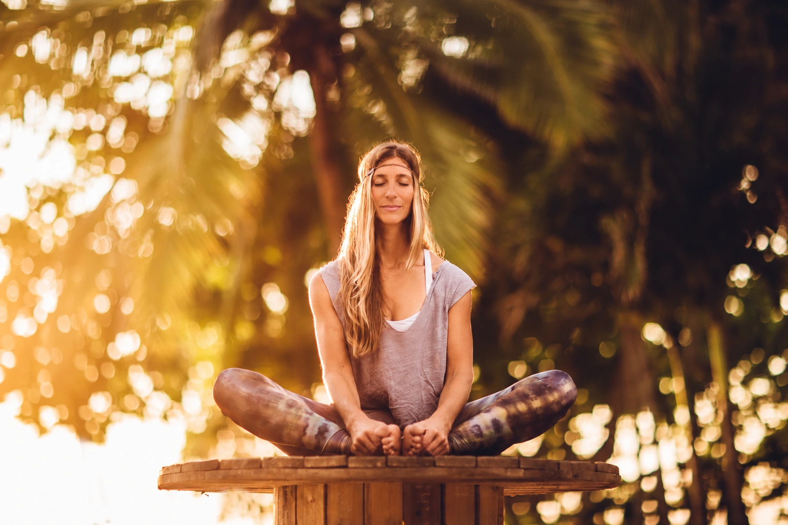 Lisa Lange beim Yoga auf einem Holzsockel im warmen Abendlicht